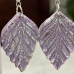 Pendientes en forma de espiga, en color malva con brillo plateado.