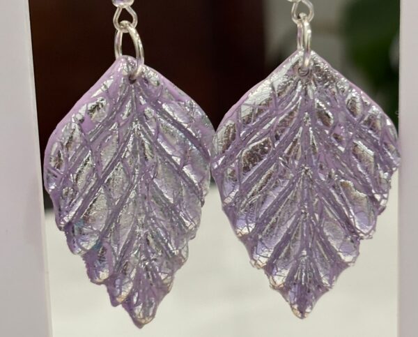 Pendientes en forma de espiga, en color malva con brillo plateado.